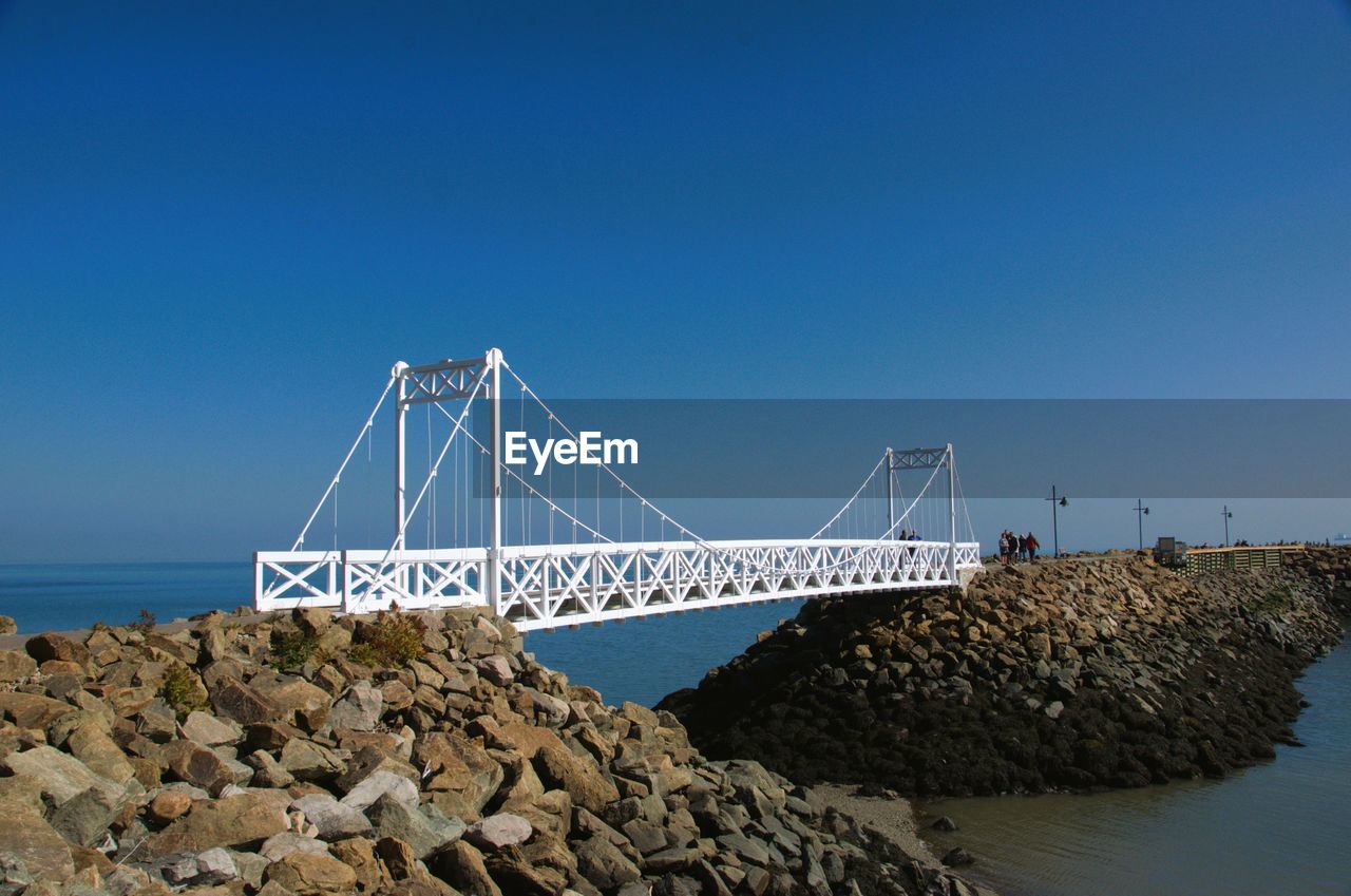 water, sky, sea, architecture, bridge, built structure, nature, transportation, coast, blue, ocean, horizon, clear sky, rock, beach, shore, travel destinations, land, copy space, travel, no people, suspension bridge, day, tourism, scenics - nature, outdoors, bay, landmark, beauty in nature, breakwater, coastline, sunny, tranquil scene, tranquility, city, horizon over water, bay of water