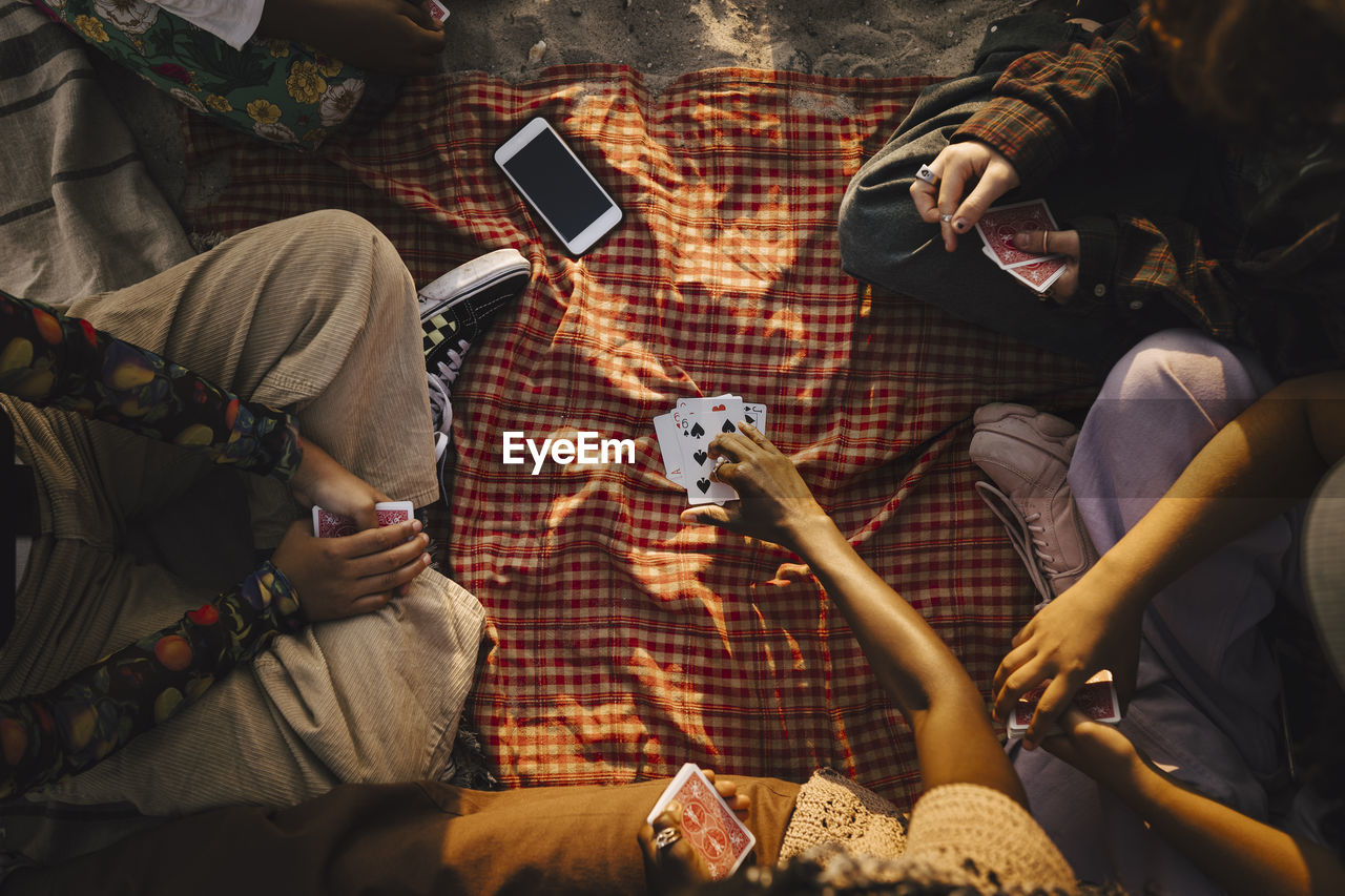 Multiracial friends playing cards at beach