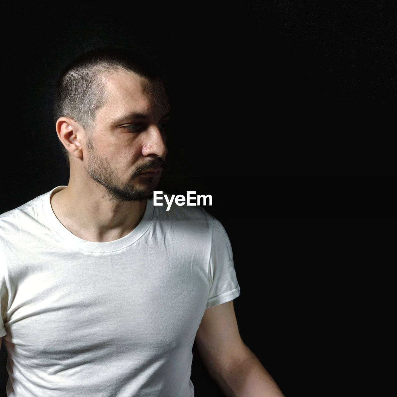 PORTRAIT OF A YOUNG MAN AGAINST BLACK BACKGROUND