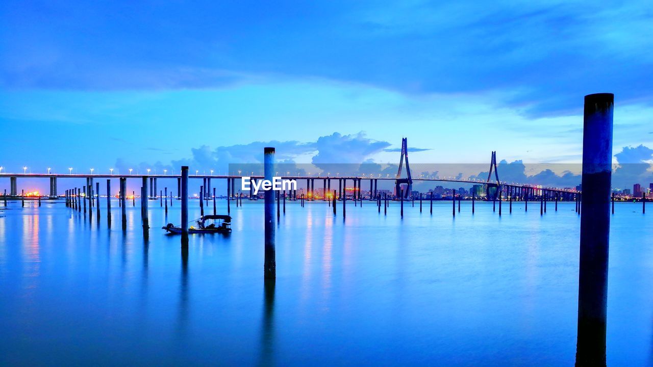 WOODEN POSTS IN SEA AGAINST SKY