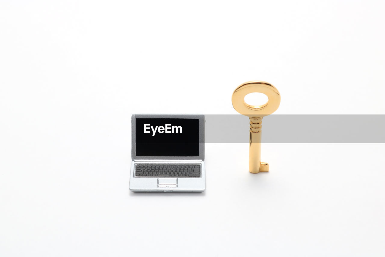 Small artificial laptop and key on white background