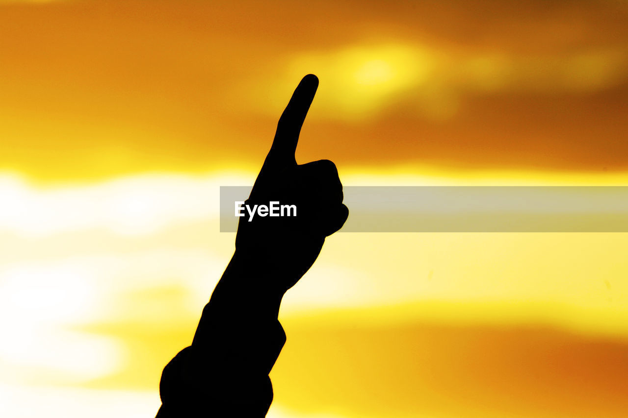 Close-up of silhouette hand against sky during sunset