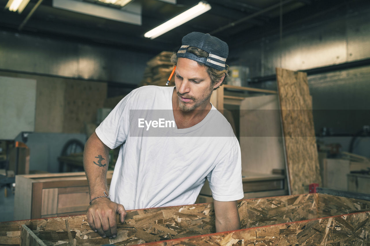 Carpenter holding wooden plank at workshop