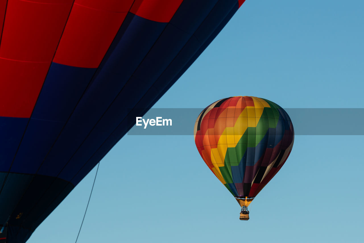 Low angle view of colorful hot air balloons flying against clear blue sky