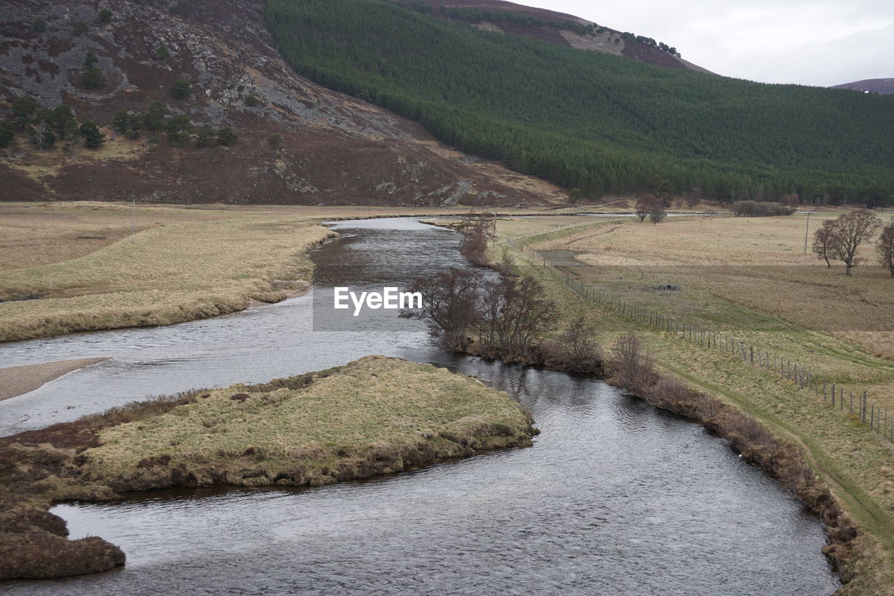 Scenic view of stream by land against sky