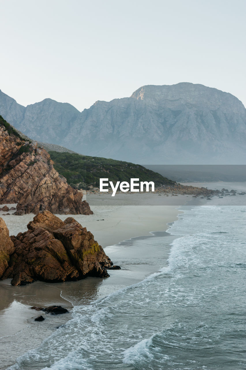 Scenic view of sea and mountains against clear sky.