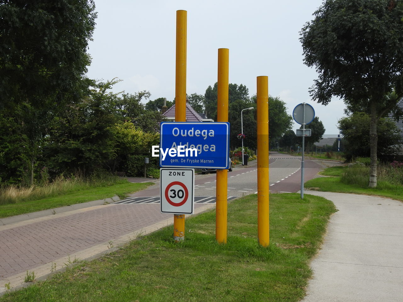 Road sign amidst trees against sky