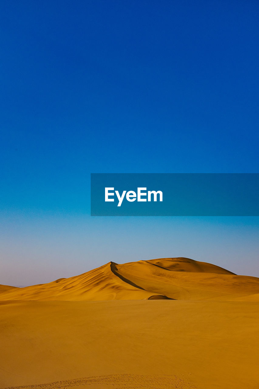 Scenic view of desert against clear blue sky