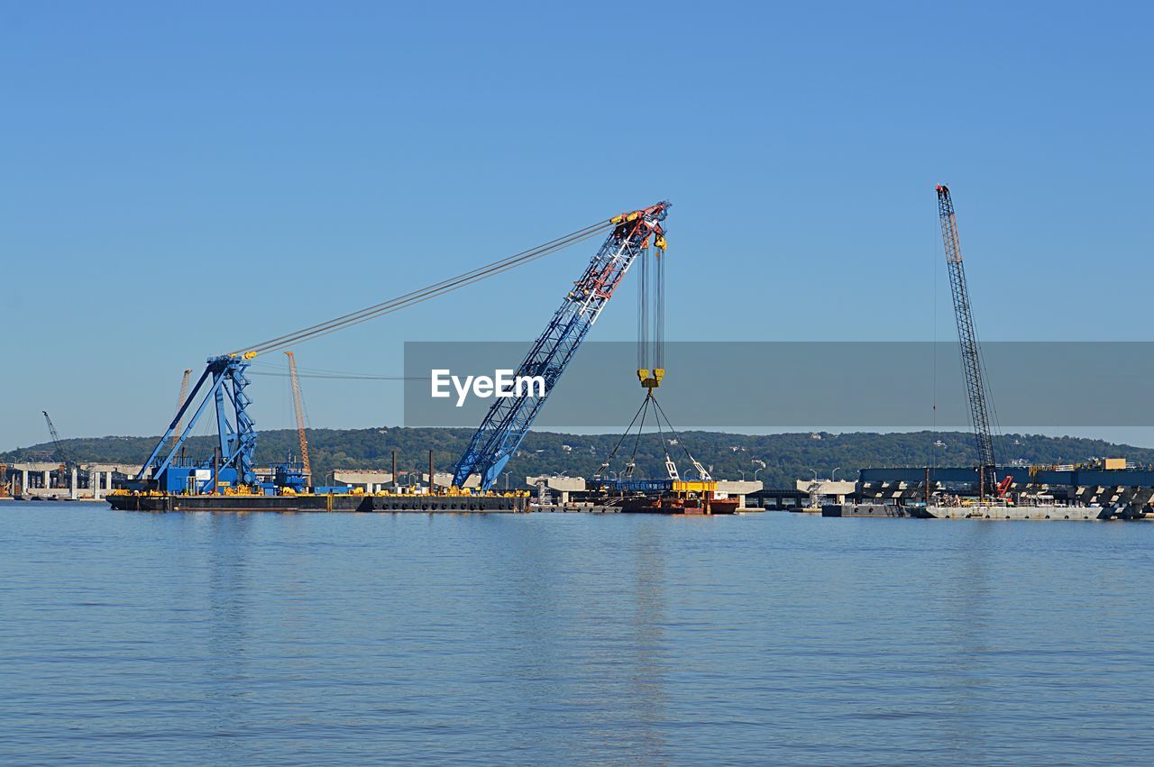 Crane at harbor against clear sky