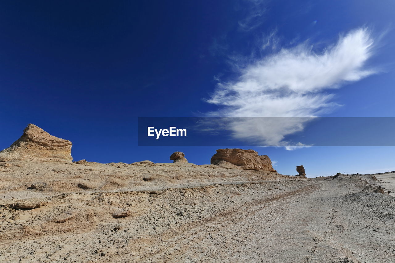 ROCK FORMATIONS ON DESERT AGAINST BLUE SKY