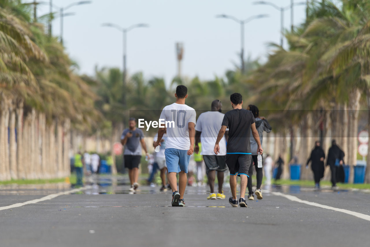 Rear view of men walking on road in city