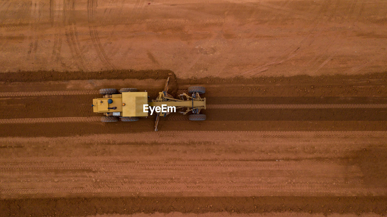 HIGH ANGLE VIEW OF TRACTOR ON FIELD AGAINST YELLOW CAR