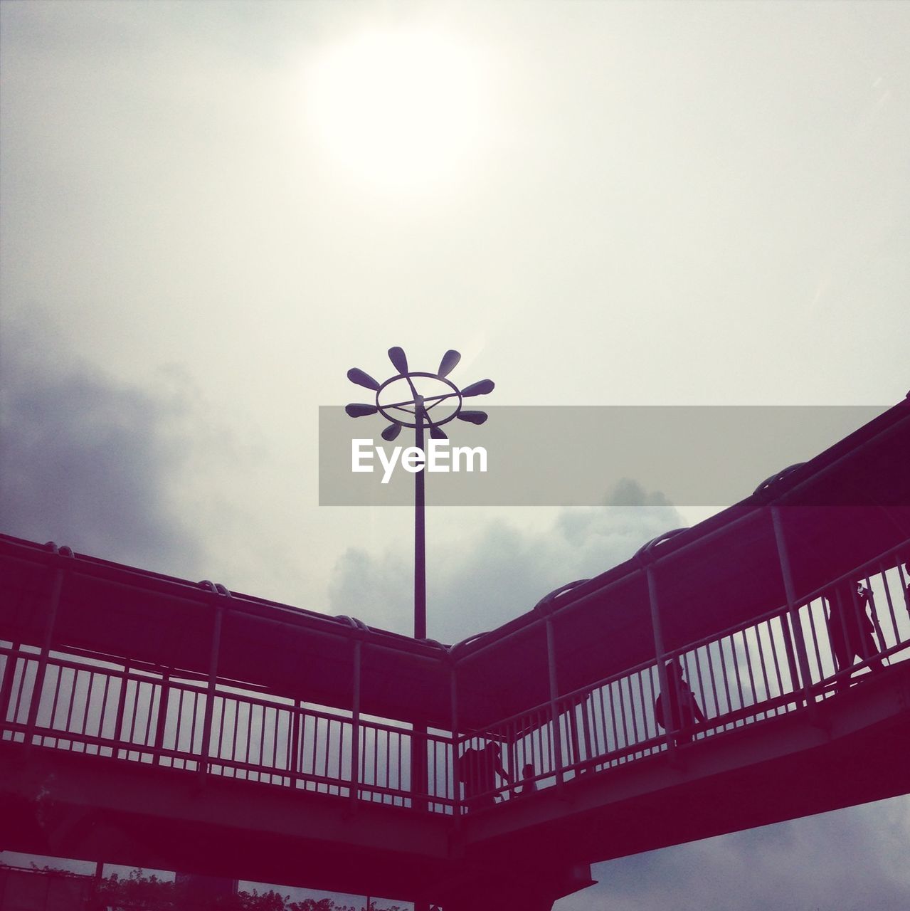 Low angle view of footbridge against cloudy sky