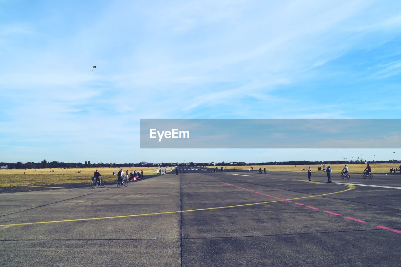 People at airport runway against sky