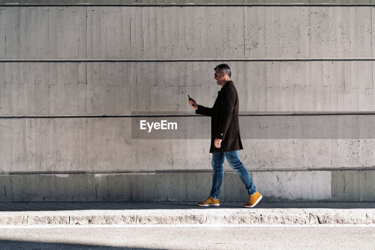 Side view of man walking on footpath