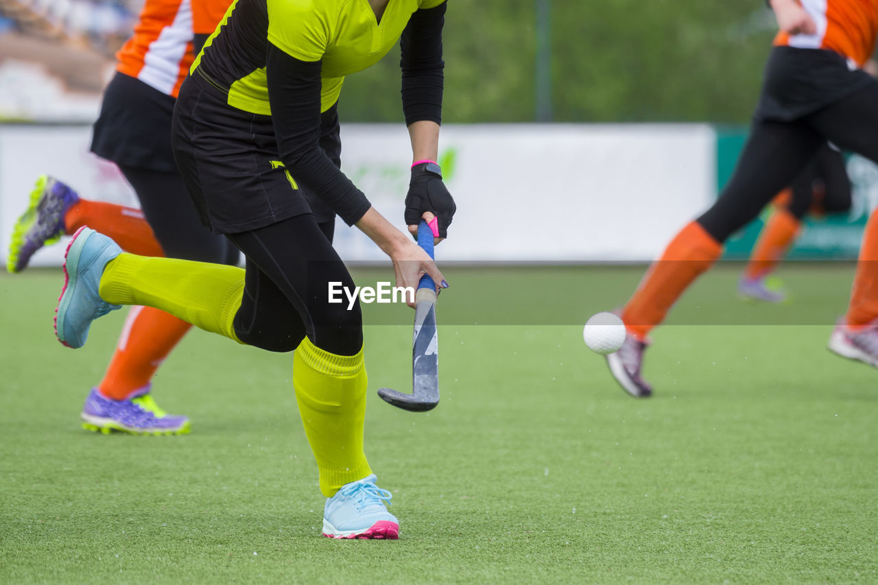 Low section of people playing hockey on field