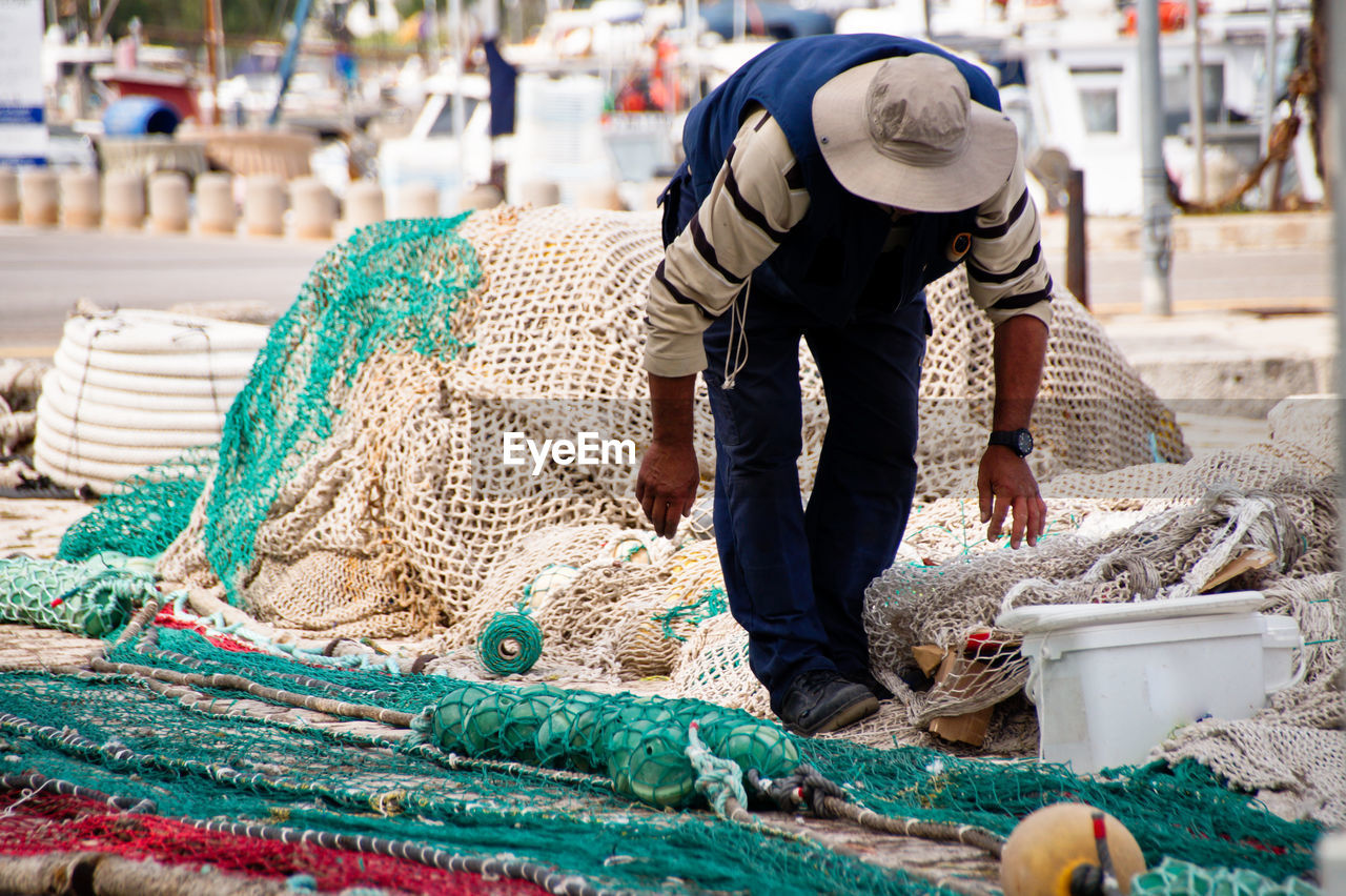 Man working at harbor amidst fishing net