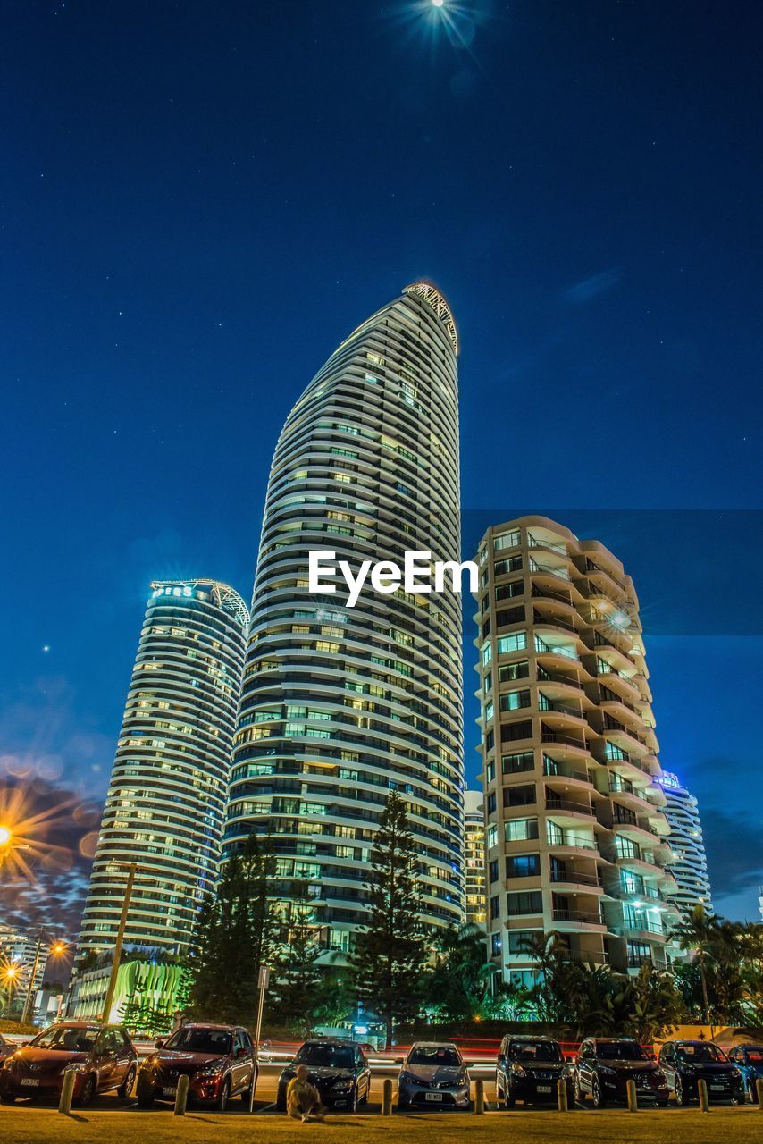 Low angle view of skyscrapers against blue sky at night