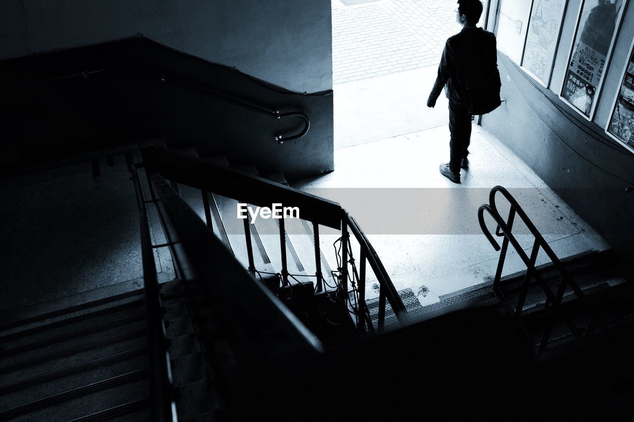 HIGH ANGLE VIEW OF SILHOUETTE WOMAN WALKING ON STAIRCASE