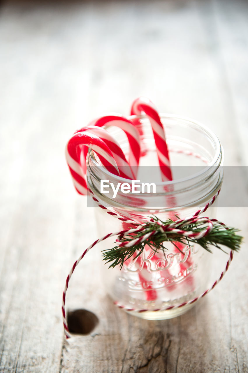 Candy canes in glass container on wooden table