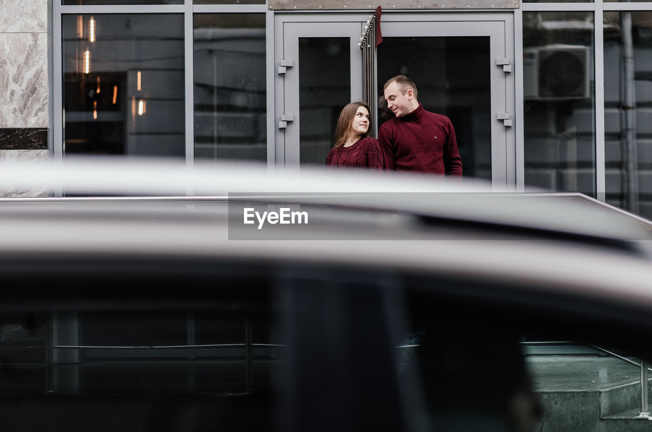 Smiling couple face to face standing against building in city