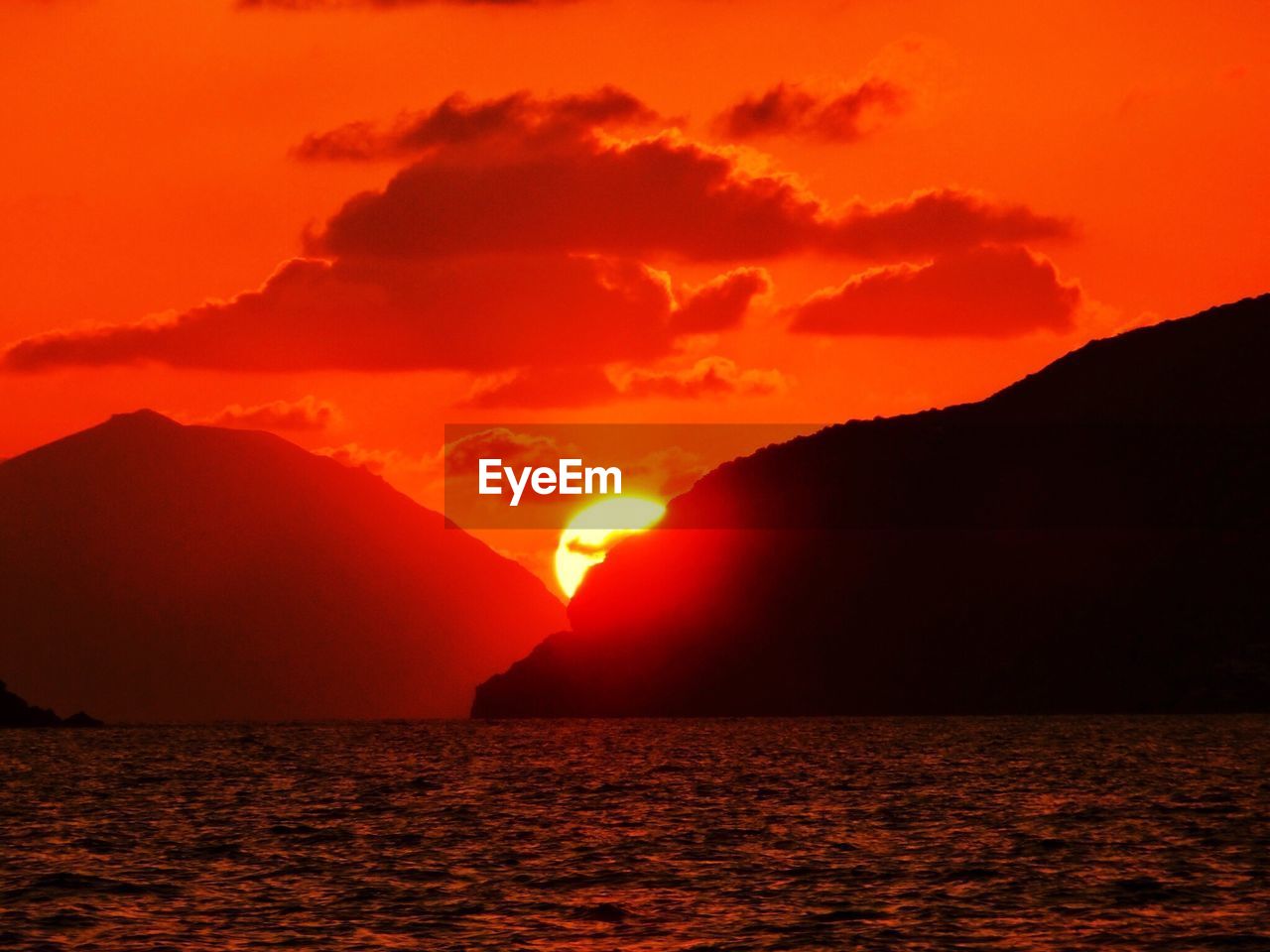 Scenic view of sea in front of mountains against sky during sunset