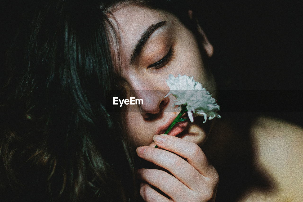 Close-up portrait of a beautiful woman with red eyes closed