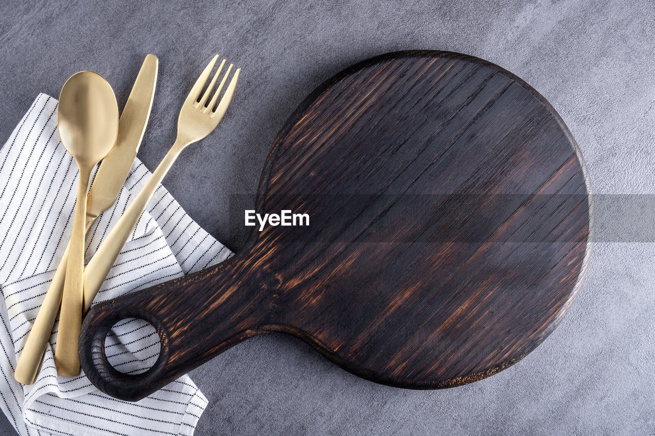 Top view background wooden cutting board or food serving board with linen napkin and cutlery. 