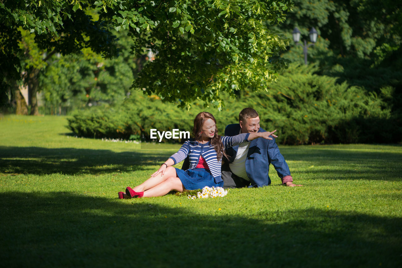 Man with woman sitting on grassy field at park