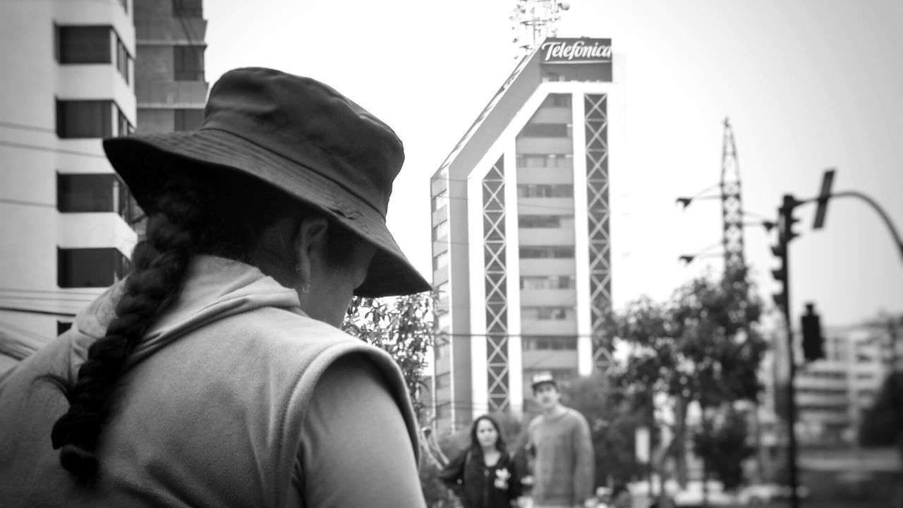 CLOSE-UP OF MAN WITH BUILDINGS AGAINST SKY