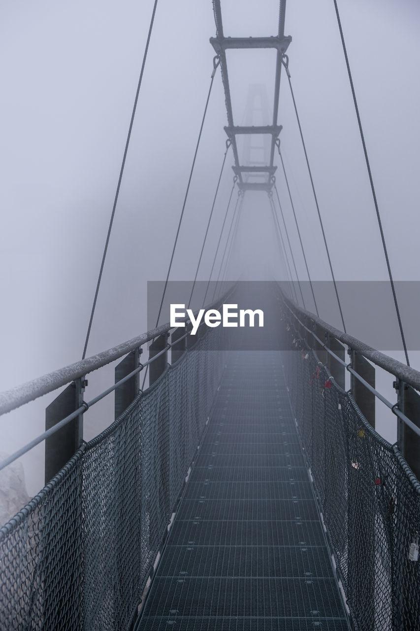 Low angle view of bridge against a wall of fog