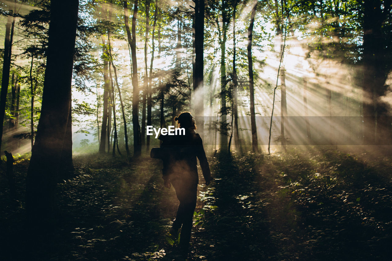 Man with backpack walking in forest against trees