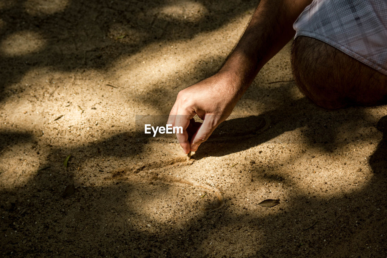 Midsection of man writing on sand at beach