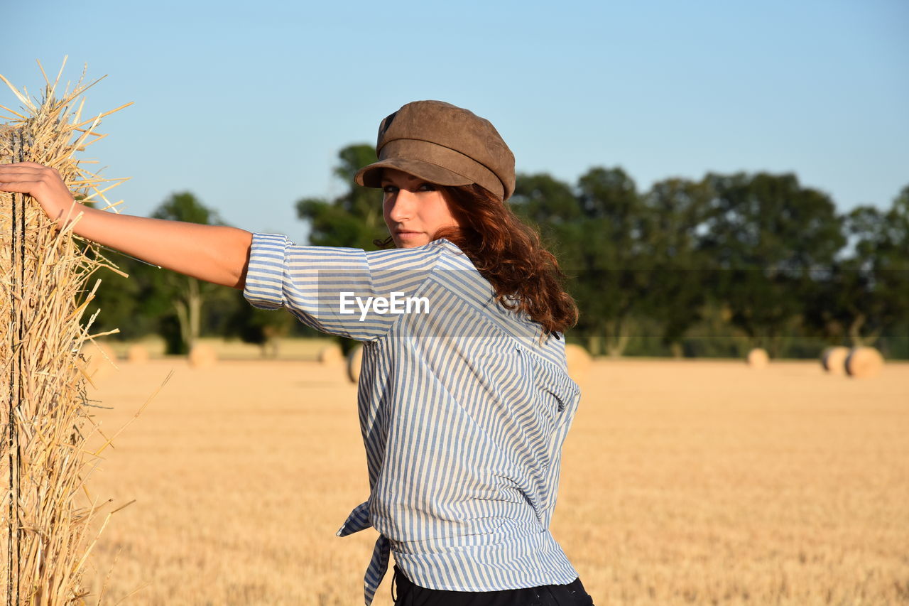 YOUNG WOMAN STANDING ON FIELD