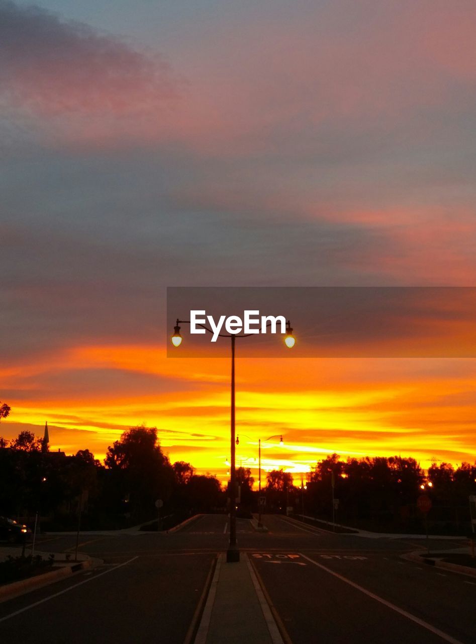 SILHOUETTE OF ROAD AGAINST CLOUDY SKY AT SUNSET