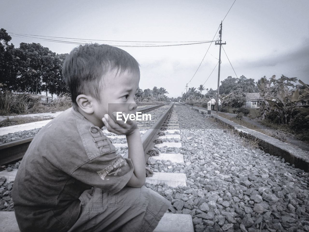 REAR VIEW OF BOY ON RAILROAD TRACK AGAINST SKY