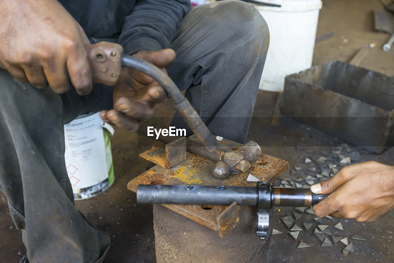 MIDSECTION OF MAN WORKING ON METAL