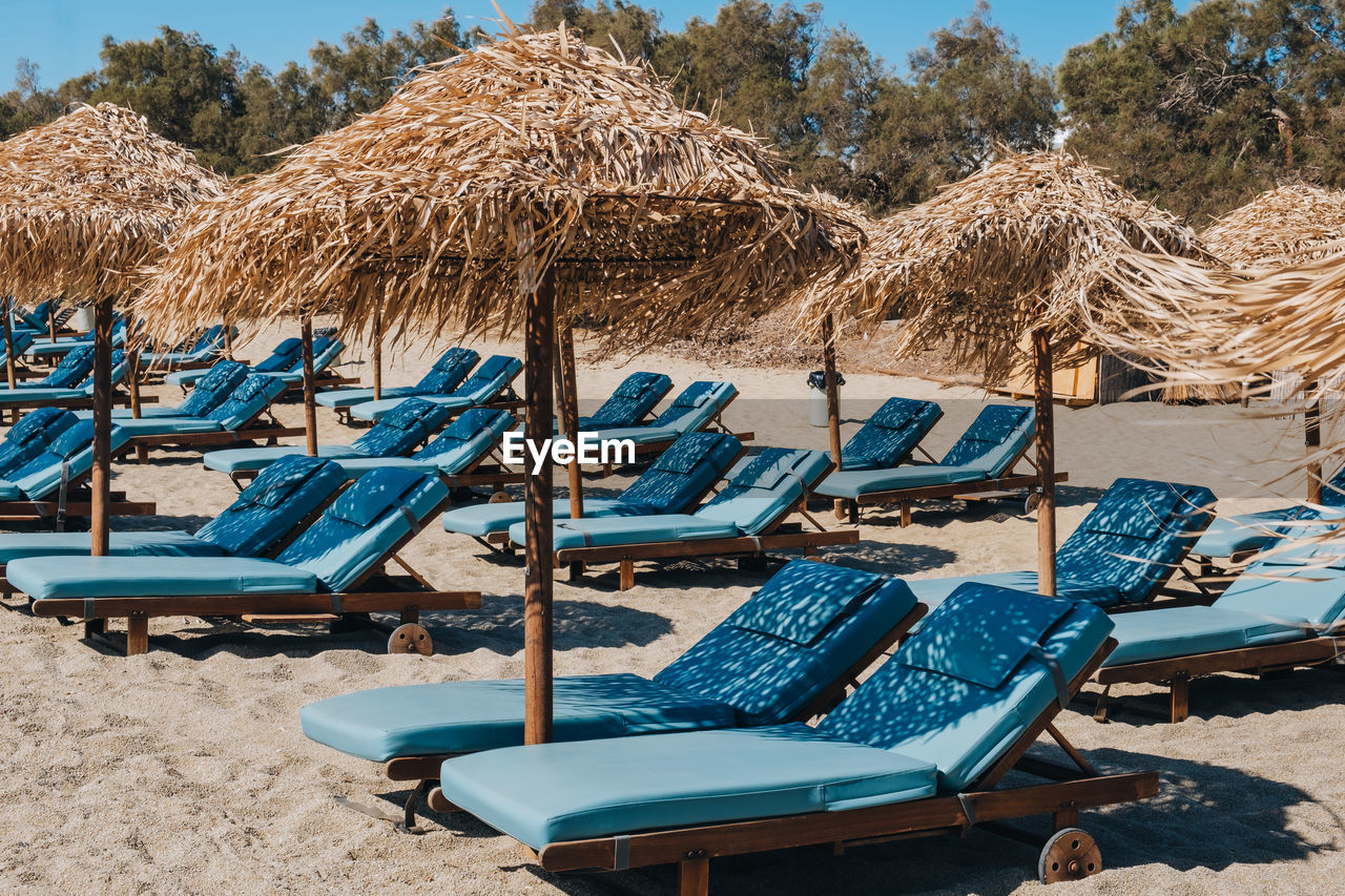 Empty blue sun beds and loungers under the umbrellas on a beach in mykonos, greece.