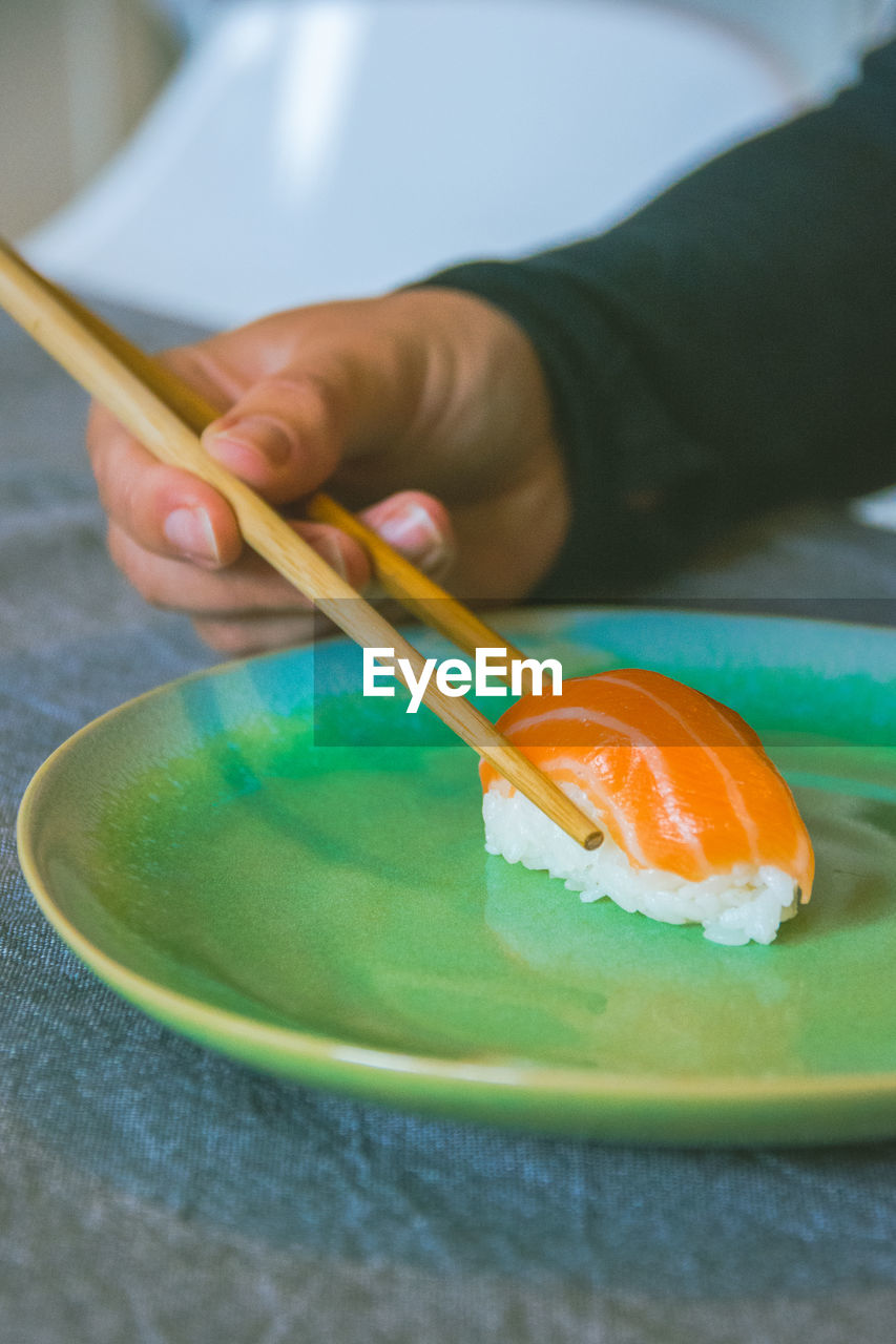 Cropped hand of person holding sushi in plate