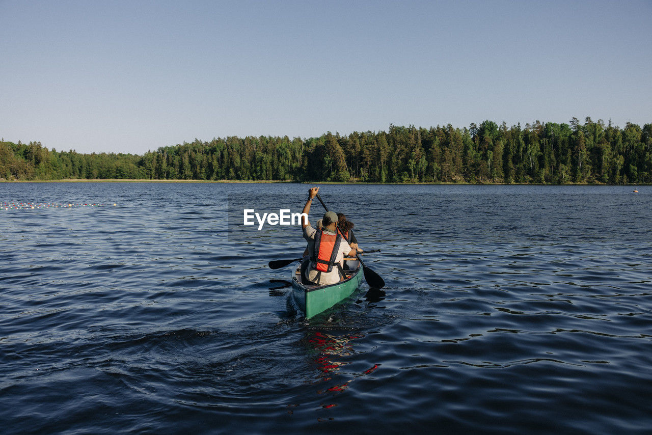 Counselor doing kayaking with kids on lake at summer camp