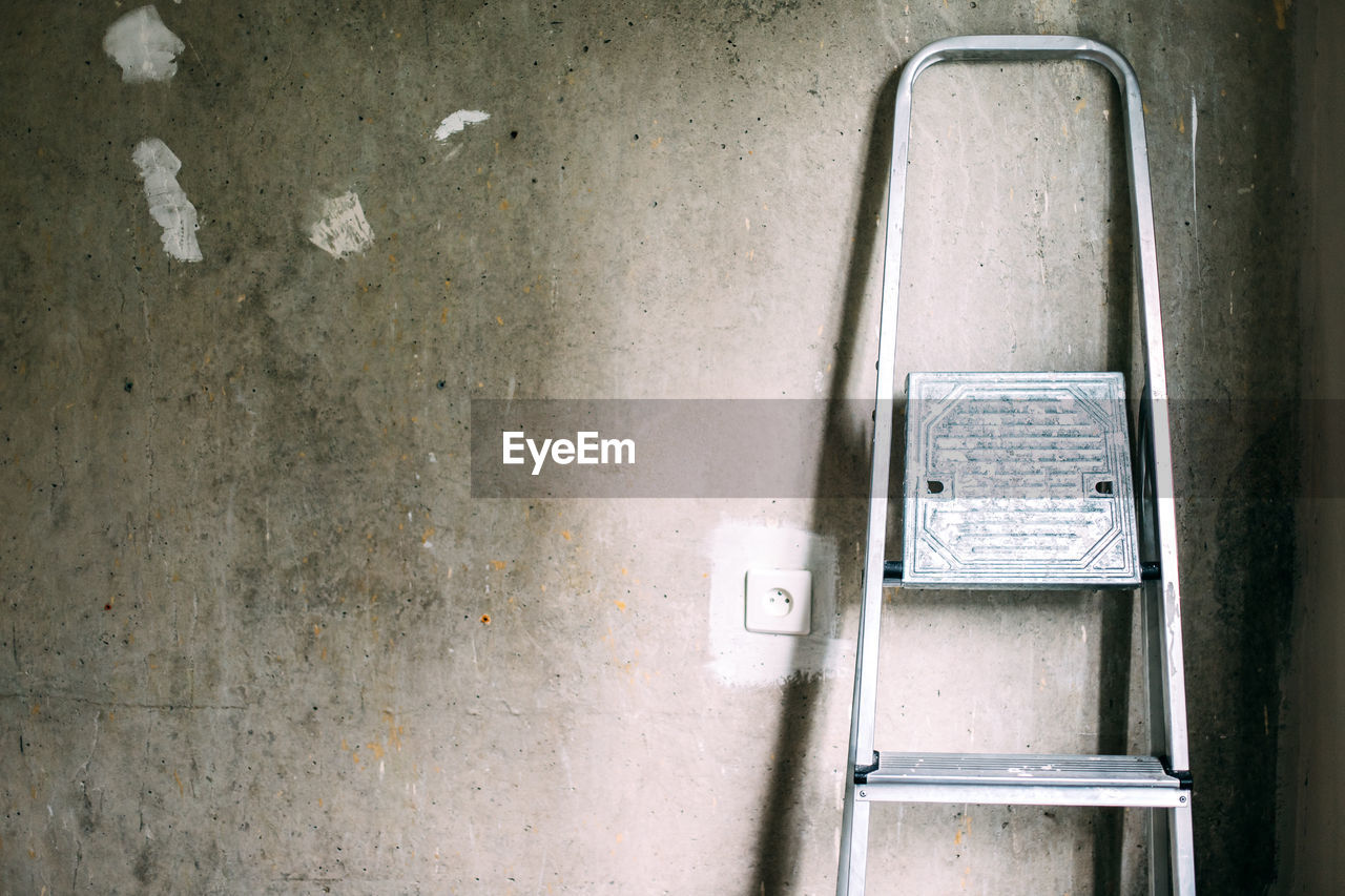 Construction ladder near a gray concrete wall