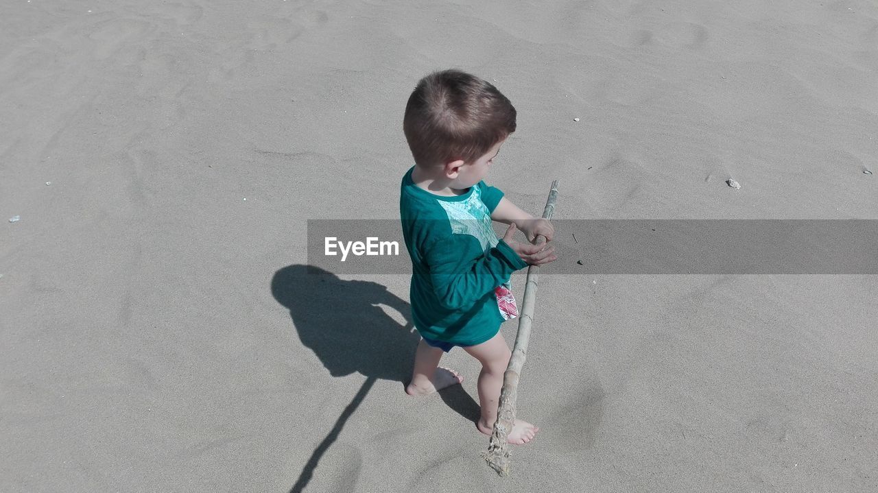 High angle view of boy playing with stick on shore at beach