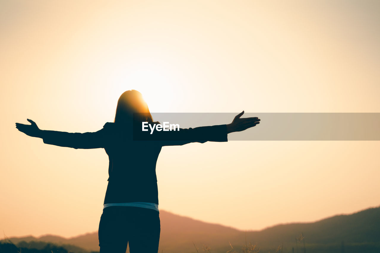 REAR VIEW OF SILHOUETTE PERSON STANDING ON MOUNTAIN AGAINST SKY