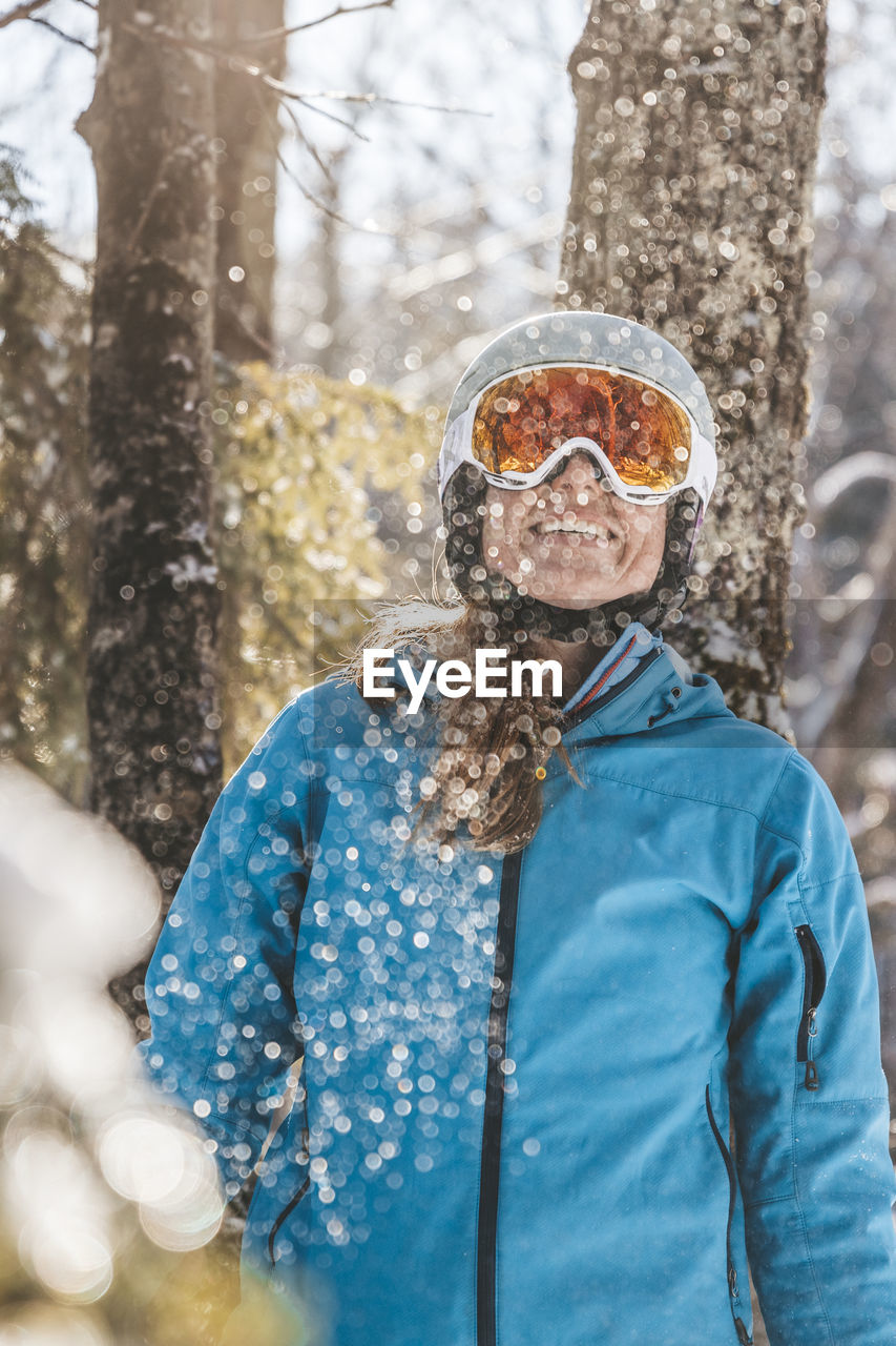 Woman in ski goggles and helmet in backlit snow scene in new hampshire