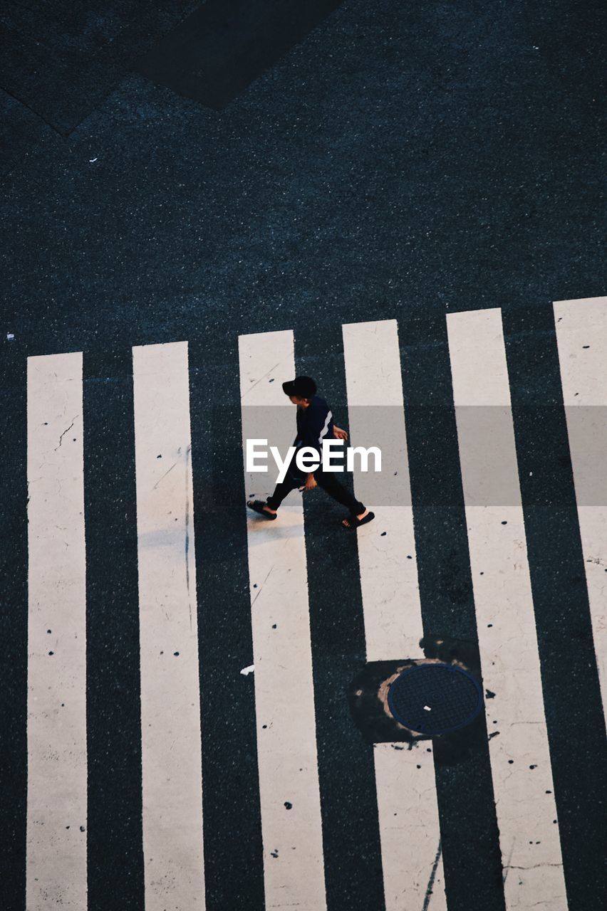 HIGH ANGLE VIEW OF MAN CROSSING STREET