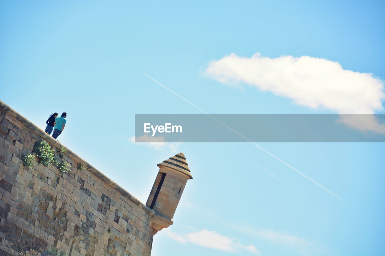 Tilt shot of couple at old cathedral of lleida against sky