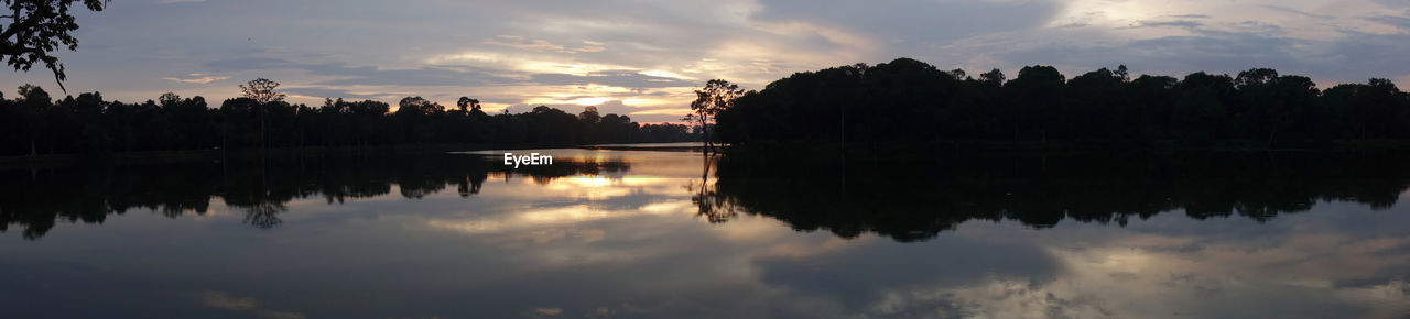 reflection, water, sky, cloud, tree, tranquility, nature, beauty in nature, lake, morning, scenics - nature, tranquil scene, dawn, plant, silhouette, no people, environment, sunrise, landscape, outdoors, sunlight, panoramic, reflection lake, idyllic, sun, twilight, travel destinations, non-urban scene, forest, body of water