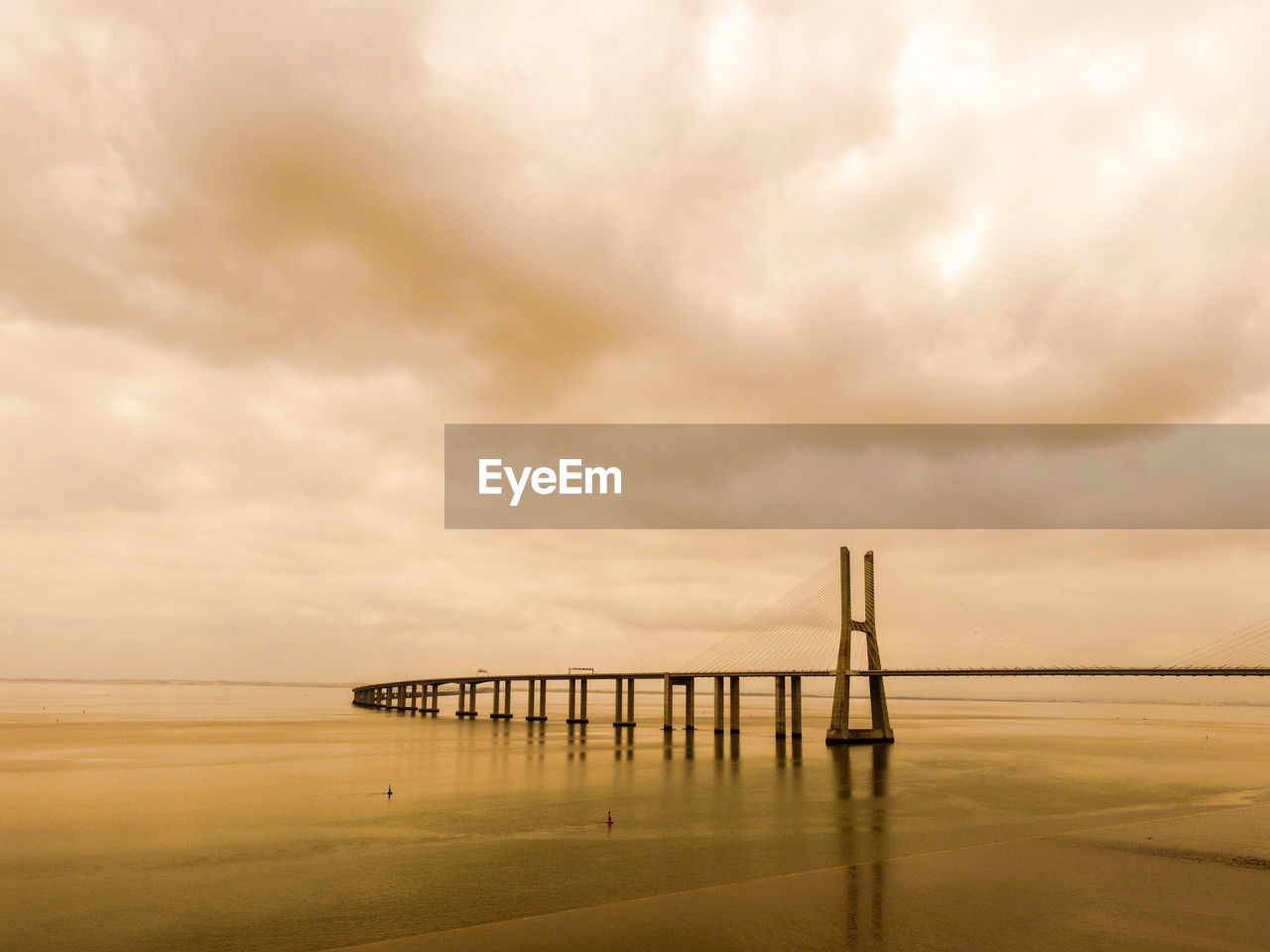 Bridge over sea against sky during sunset