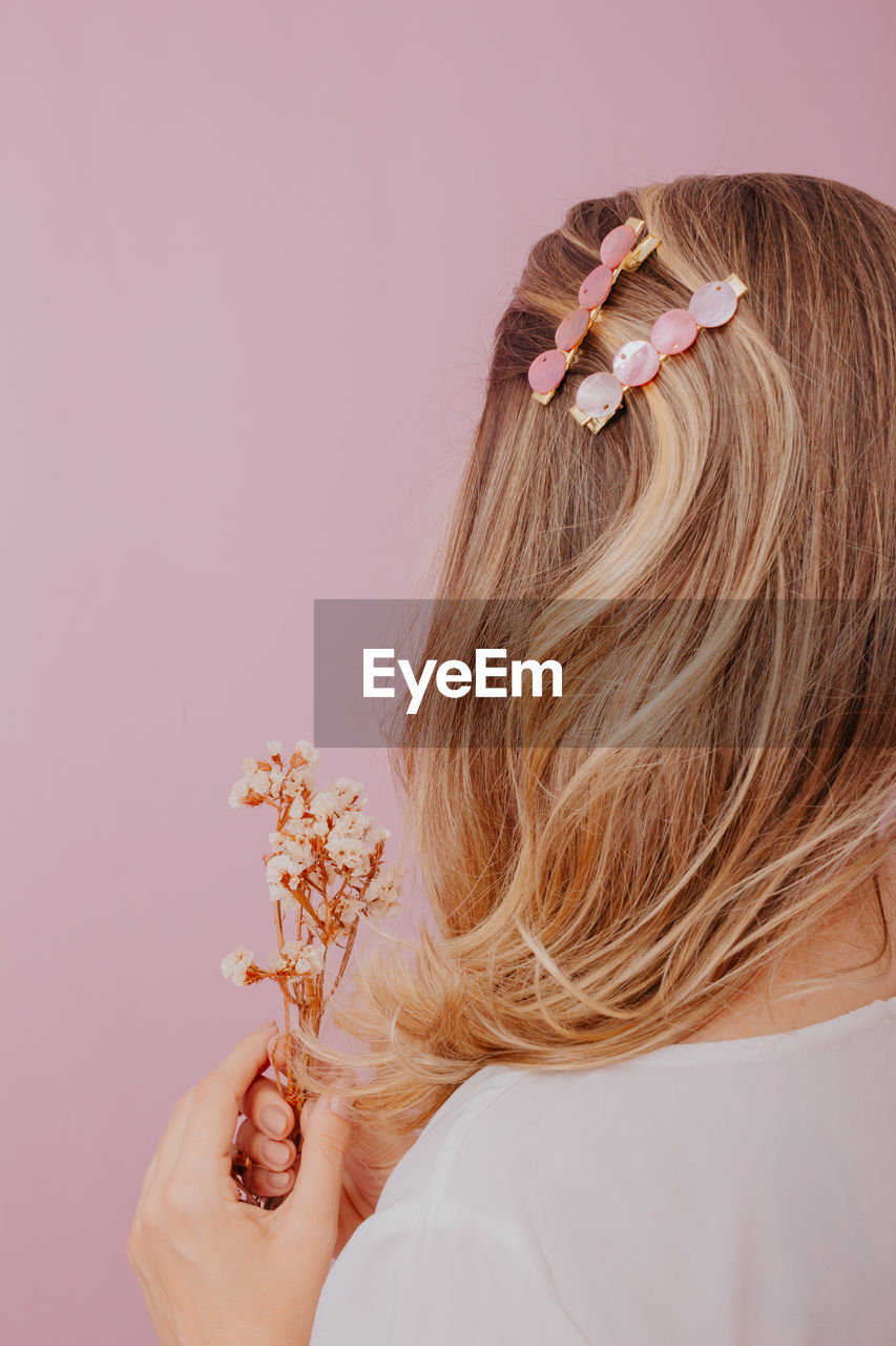 Woman holding pink flower against white background