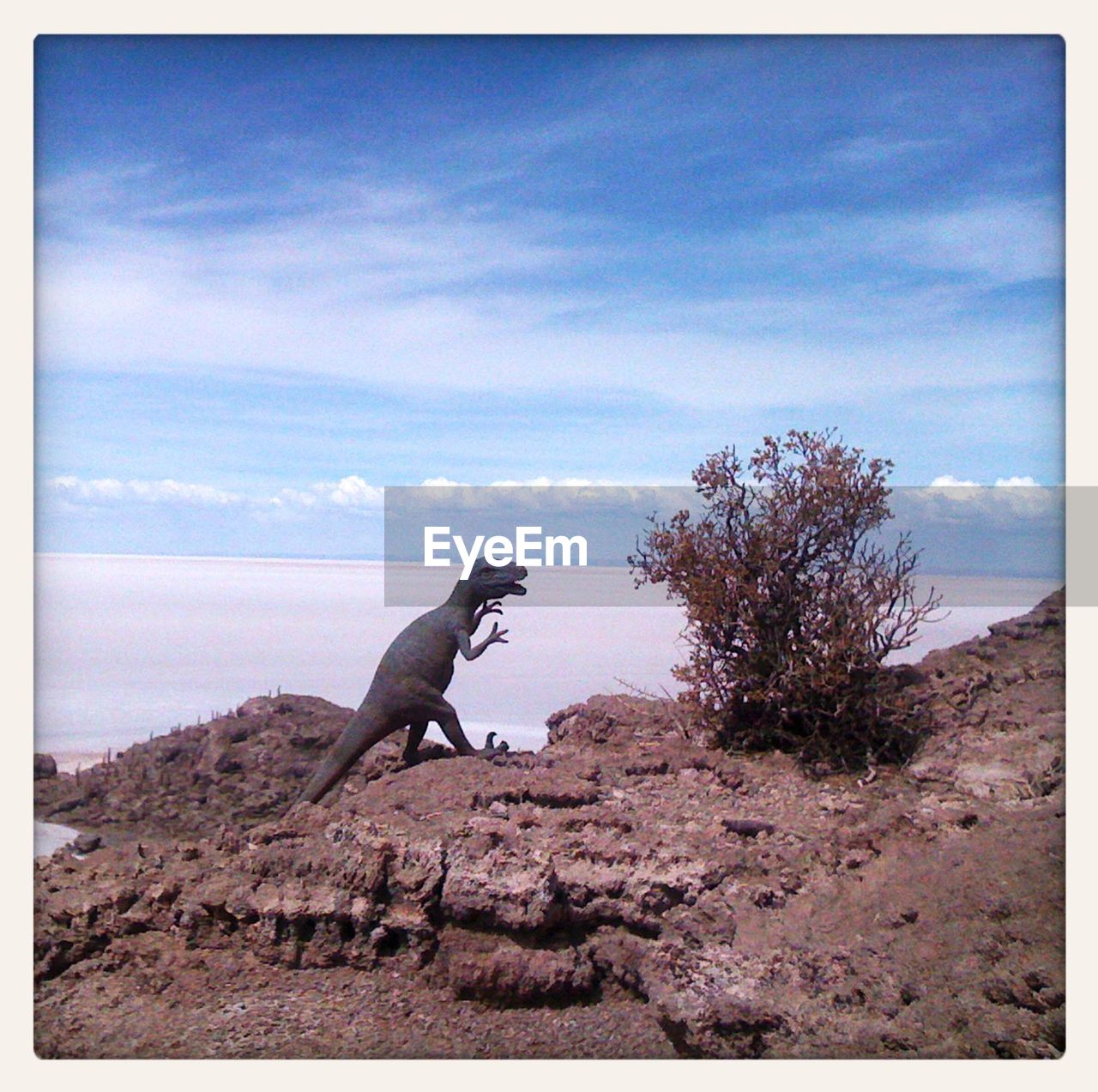 Dinosaur on mountain by salar de uyuni against sky